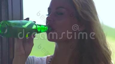 年轻女子在夏天炎热的日子喝啤酒瓶。 在夏天，让美丽的女孩喝瓶冰镇啤酒